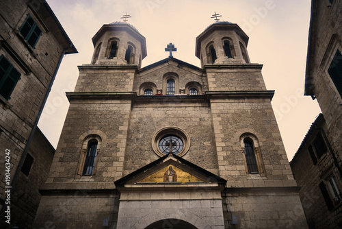 Looking up view of historic stone church facade with symmetrical twin bell towers and central entrance. Church of St. Nicholas, Kotor, Montenegro. 
