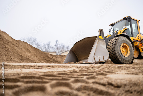 Front loader digging into sand at construction site