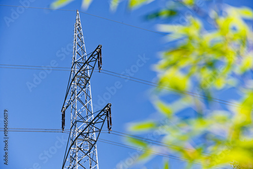 High voltage power line tower against blue sky representing energy infrastructure
