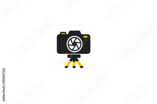 Camera on tripod with a black body and yellow legs sits ready for use in a bright space during daytime