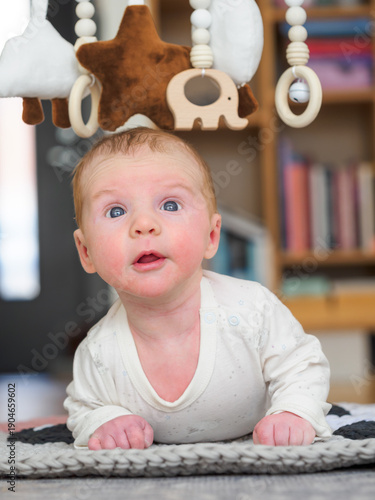 Cute two month old baby boy lies on tammy and looking up for toys