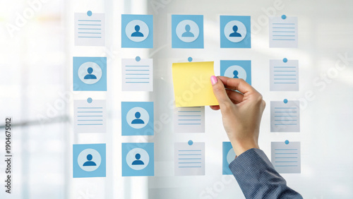 Human resources recruitment concept with hand placing sticky note on transparent board showing candidate profiles and resumes