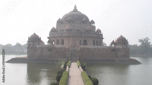 historic causeway approaching sher shah suri mausoleum, surrounded by calm lake water and peaceful atmosphere 