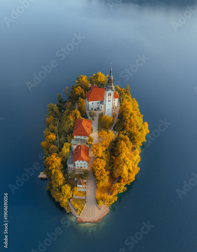 Foto Aerial view of Lake Bled island surrounded by golden autumn foliage, featuring t