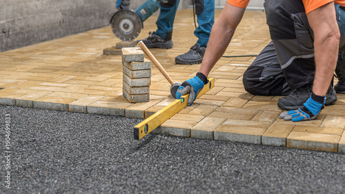 Laying interlocking paving. Leveling the block using a spirit level.