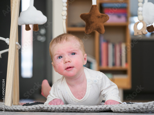 Cute two month old baby boy lies on tammy and looking up for toys