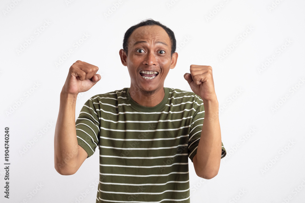 Fototapeta premium A man wearing a green shirt with white stripes is raising his hands up in the air in a gesture of celebration or victory.