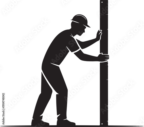 A construction worker wearing a hard hat pushes or installs a large vertical wooden post or beam
