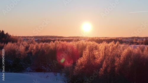 4K aerial drone ascent reveal of Lithuania winter landscape at golden hour, bright sunset over frosted trees and snowy forest canopy, cinematic nature view