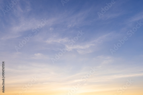 Foto Beautiful sunset sky with orange clouds and blue gradient background,Vibrant sunset sky featuring soft wispy clouds illuminated by golden light, transitioning from deep blue to bright orange