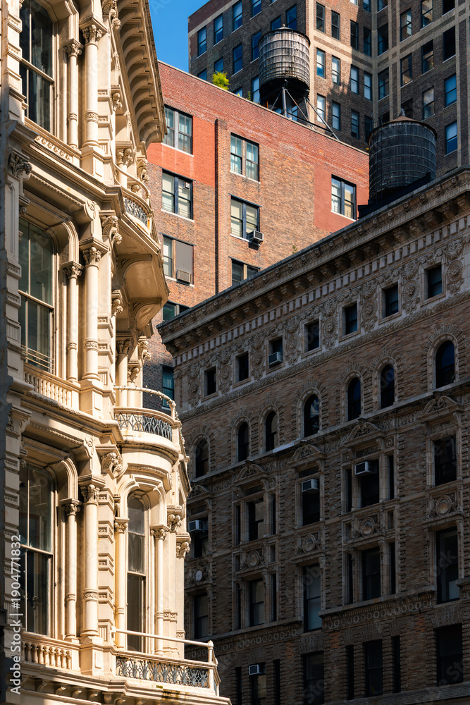 Obraz premium New York City, Flatiron District, Manhattan, along Broadway. Architectural detail featuring ornate building façades and rooftop water towers in strong sunlight