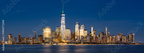 Panoramic view of New York City Lower Manhattan skyline at dusk with the Hudson River. Illuminated skyscrapers of the Financial District and World Trade Center