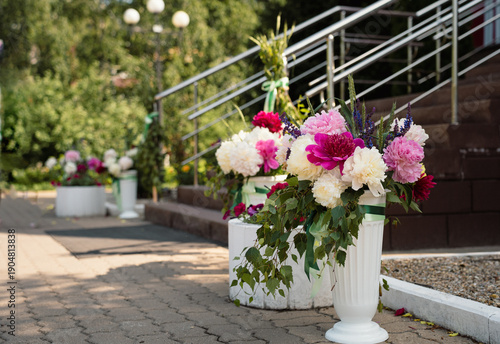 Summer bouquet of white, scarlet, pink terry blooming peonies in a vase by the porch