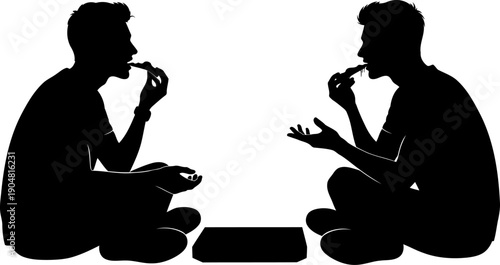 Two men sitting on the floor eating pizza and talking silhouette