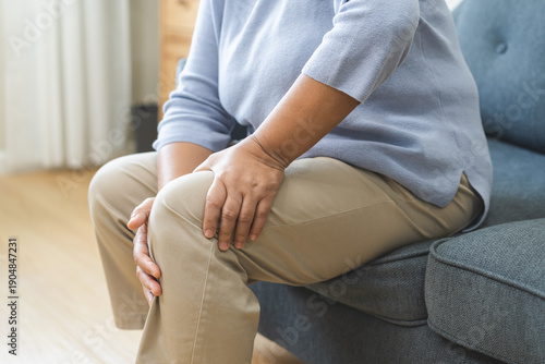 Bilde på lerret Body arthritis muscles stiff problem, aged woman suffering on leg, pain knee from disease chronic, hand massage rubbing joint injury, mature hurt or sore sitting on sofa at home