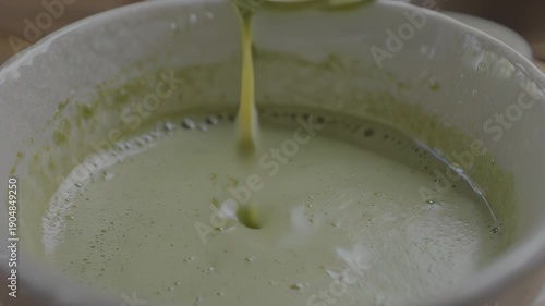 Wallpaper Mural Whisking green matcha tea powder in a white bowl, creating a smooth mixture with visible swirling patterns and a wooden whisk in motion during the preparation process, hdr video with neutral color Torontodigital.ca