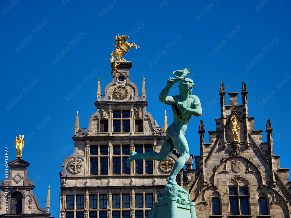 Fototapeta premium Brabo Fountain Grote Markt Antwerp Clear Sky - Wide-angle view of the Brabo Fountain and historic guildhalls on the Grote Markt (Great Market Square) in Antwerp, Belgium, under a clear blue sky.