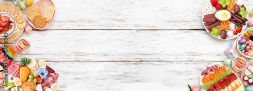 Spring or Easter grazing board theme double border against a white wood banner background. Top view. Variety of sweets and cheese, meat and fruit appetizers. Copy space.
