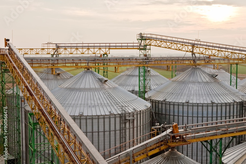 Aerial view of industrial grain silos and conveyor bridges at sunset.