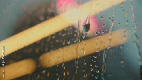 Raindrops on glass with city lights creating urban atmosphere