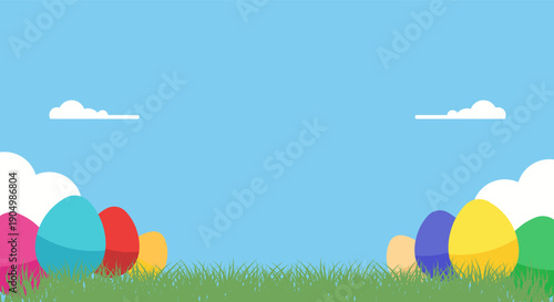 Brightly colored Easter eggs nestled in green grass under a clear blue sky with clouds