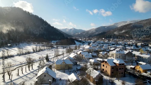 Aerial drone view of houses in a village near snow-covered mountains with pine trees in winter. Aerial panoramic drone view from above, top view from drone.  Ukraine, Carpathians, Skole city
