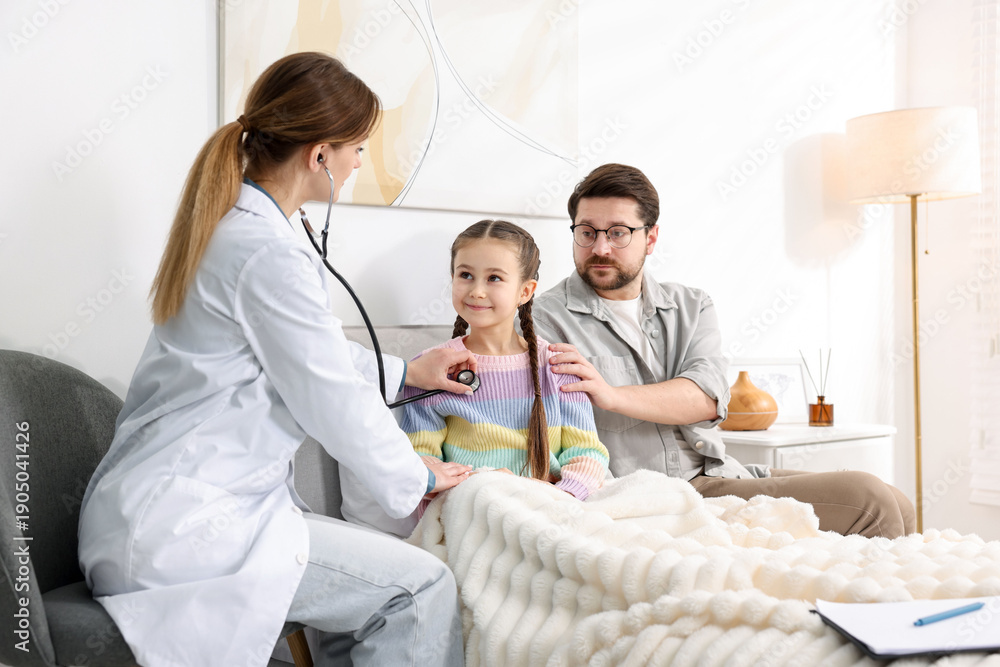 Fototapeta premium Little girl and her father having pediatrician visit at home. Doctor examining child with stethoscope