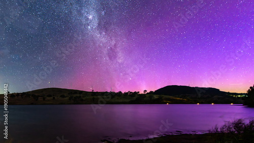 Fotografie A Pink Aurora Australis and the Milky Way Shimmers Over the Dam