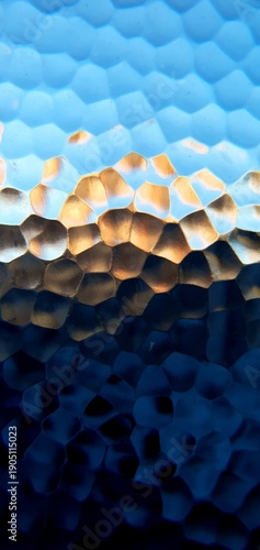 Abstract frosted glass texture with blue and golden light refraction. Modern honeycomb geometric pattern and soft bokeh distortion, perfect for technology backgrounds and web design