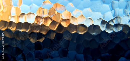 Abstract frosted glass texture with blue and golden light refraction. Modern honeycomb geometric pattern and soft bokeh distortion, perfect for technology backgrounds and web design