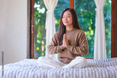 Wallpaper Mural Portrait image of a woman put hands together in a prayer and meditating on the bed at home Torontodigital.ca