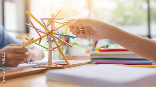 Guiding hands assemble a colorful wooden windmill in a sunny classroom.