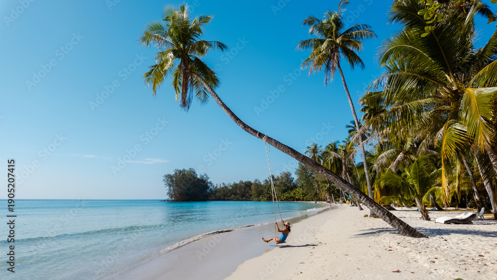 Fototapeta premium Relaxing on a tranquil swing at Khlong Hin Beach, Koh Kood, Thailand under the bright blue sky