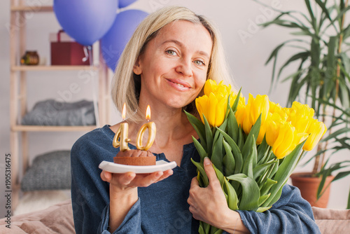Wall Mural Portrait of happy middle aged woman holding birthday cake with lit candles