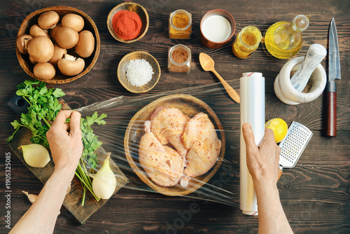 Hands wrapping marinated chicken with plastic stretch film for marinating or storage
