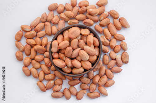 shelled peanuts in a bowl with nuts scattered around