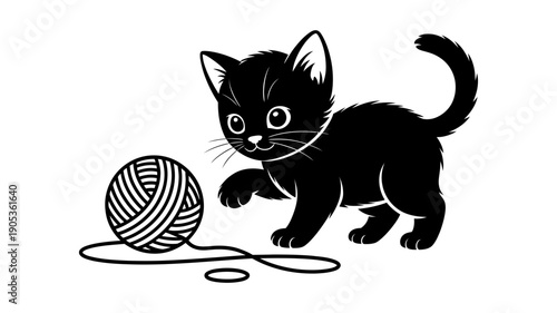 A cute little black kitten playfully bats at a ball of yarn