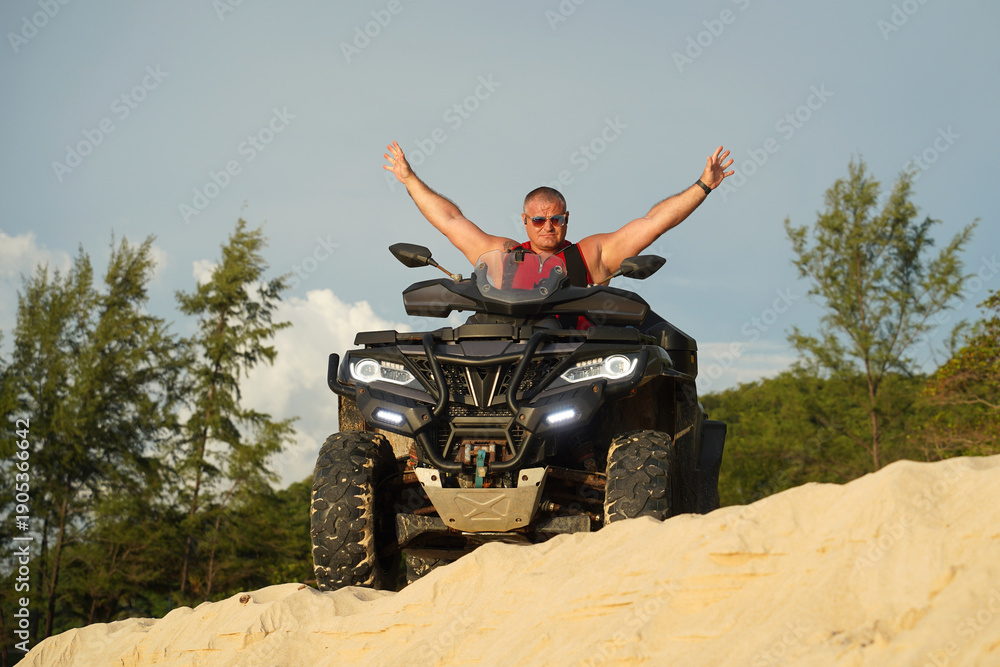 Fototapeta premium A man engages in extreme ATV riding on sand beach early in the morning