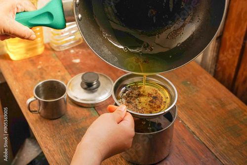 Tableau sur toile A woman’s filtering used cooking oil from non stick pan into a stainless steel c