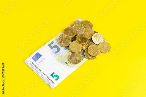 Wallpaper Mural Pile of euro coins scattered on a five euro banknote against a bright yellow background Torontodigital.ca