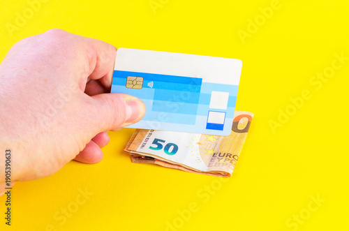 Wallpaper Mural Hand holding a credit card over euro banknotes on a bright yellow background Torontodigital.ca