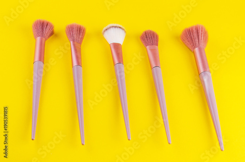 Wallpaper Mural Collection of five makeup brushes with pink bristles and lilac handles arranged on a yellow background Torontodigital.ca