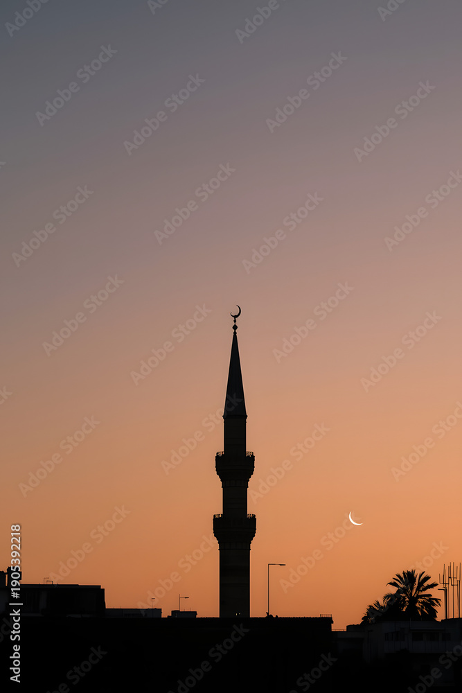 Obraz premium Minaret silhouette against a vibrant orange sunset sky