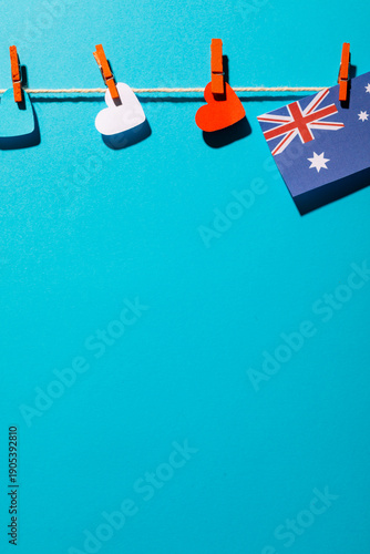 Australia flag and heart shapes hanging on clothesline with copy space over blue background