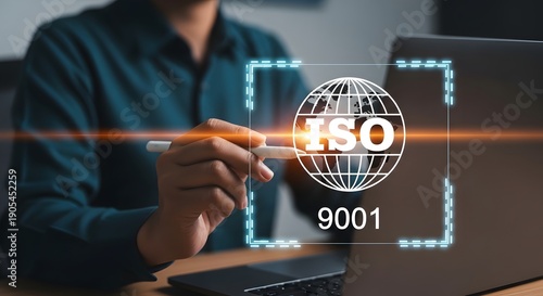 A businessman interacts with a holographic ISO 9001 certification interface on a laptop screen