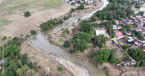 Aerial view of a winding river through a rural landscape with trees and houses.