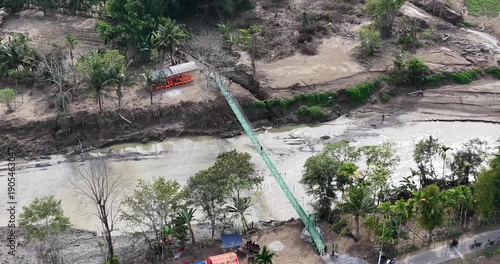 Aerial view of a suspension bridge over a muddy river.
