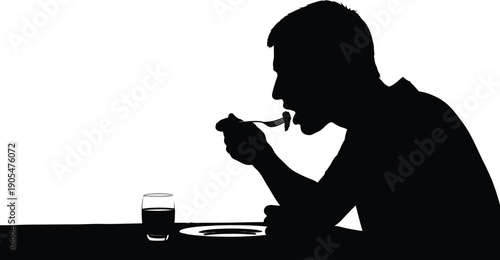 Man sitting alone eating meal from plate with glass of drink beside it in silhouette profile view