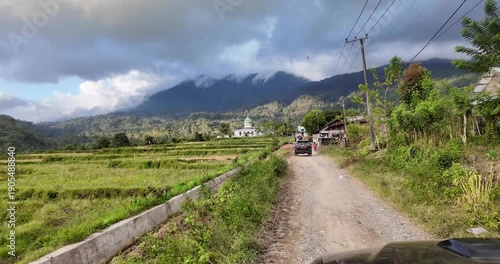 Rural landscape with dirt road and mountainous background.
