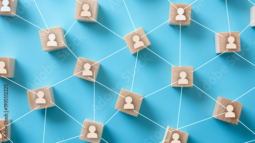Connected People Network on Blue Background. Overhead shot of wooden cubes with person icons connected by white lines, arranged on a vibrant blue background. This image represents concepts like networ